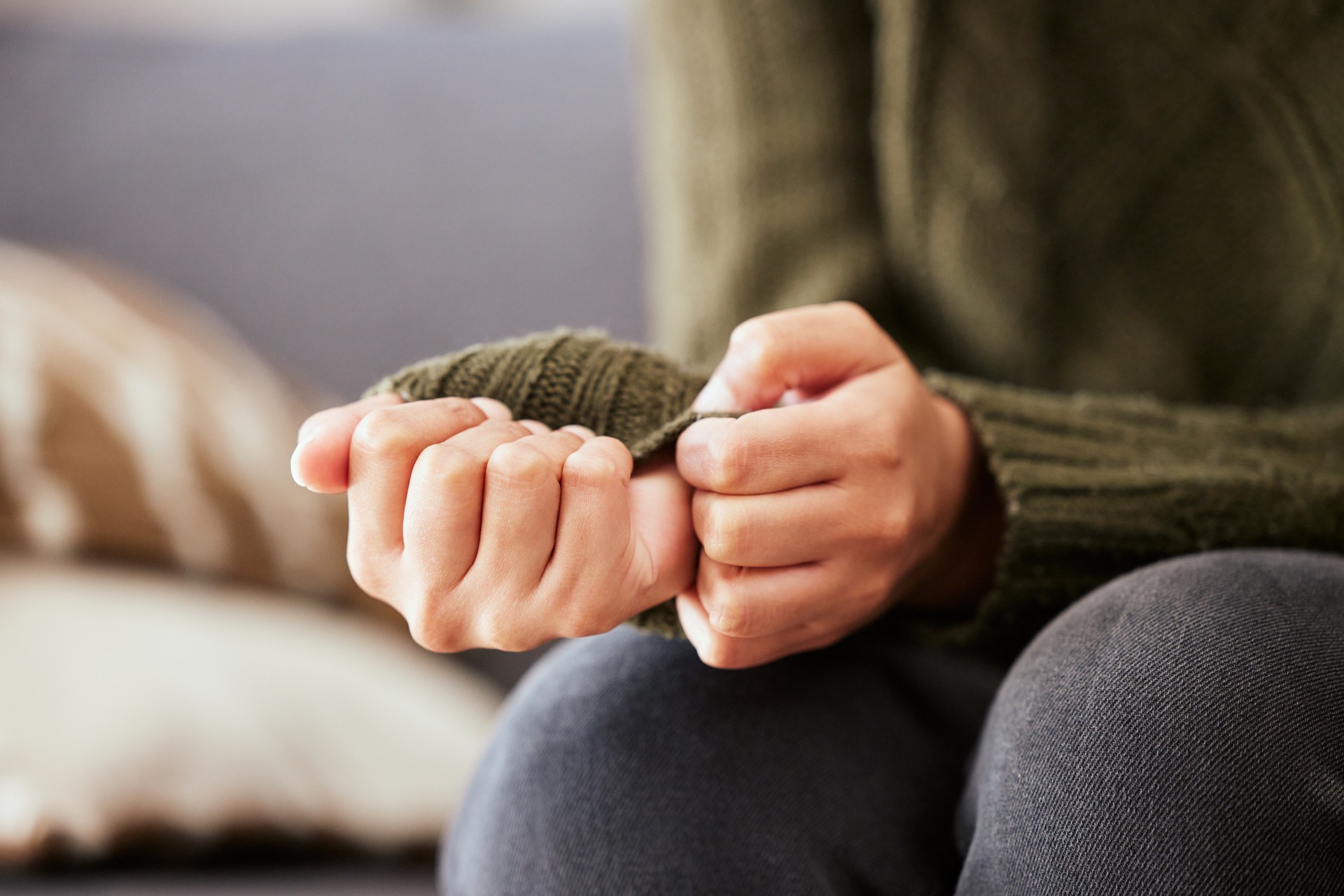 Shot of a unrecognizable woman sitting on a sofa and feeling anxious